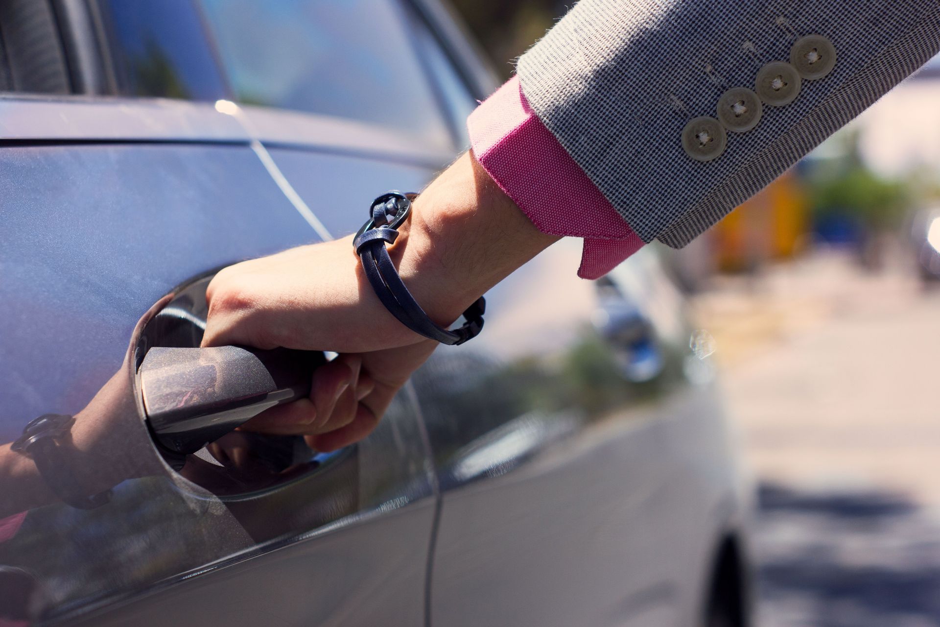 Close-up of a hand opening a car door showcasing elegant attire and style.